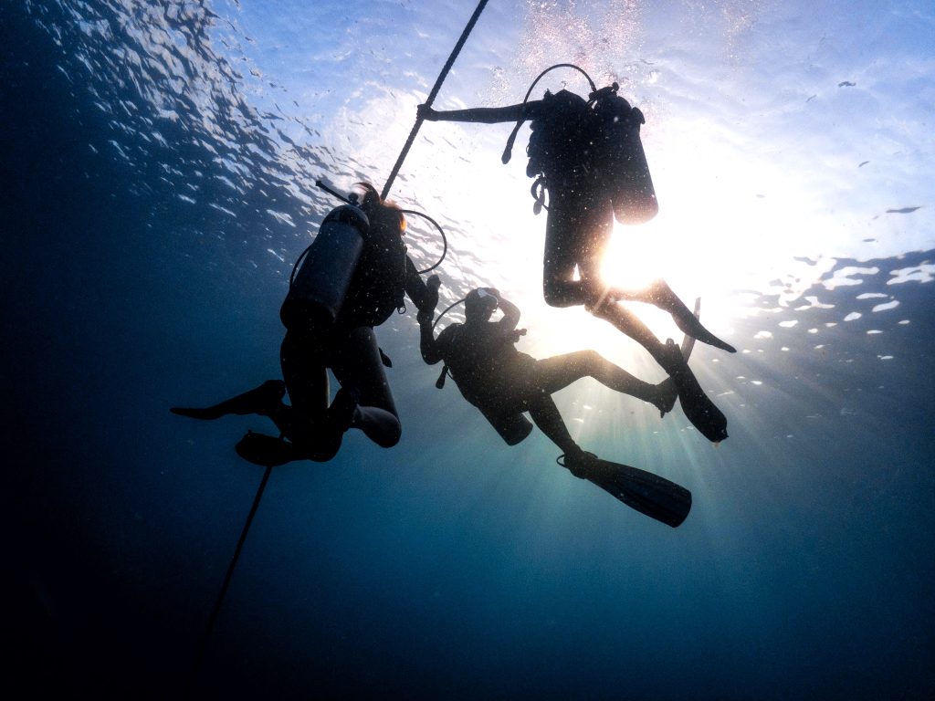 Scuba diving instructor training a small group of professional divers near a coral reef in Koh Tao's clear waters.