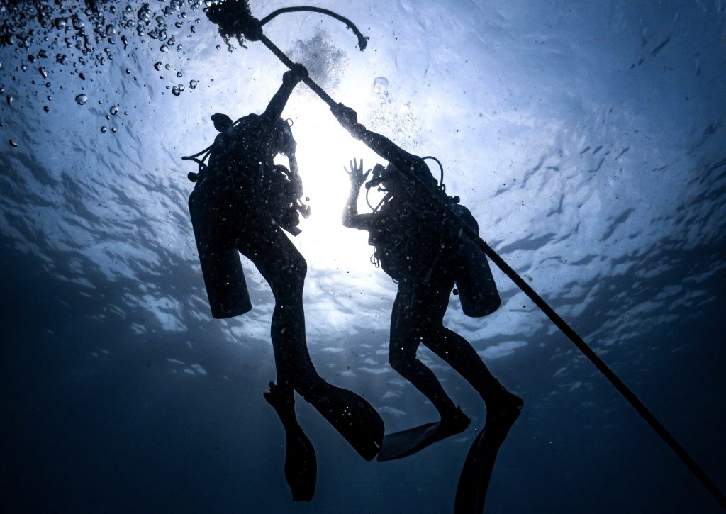 a scuba divers reaching for a pole. 