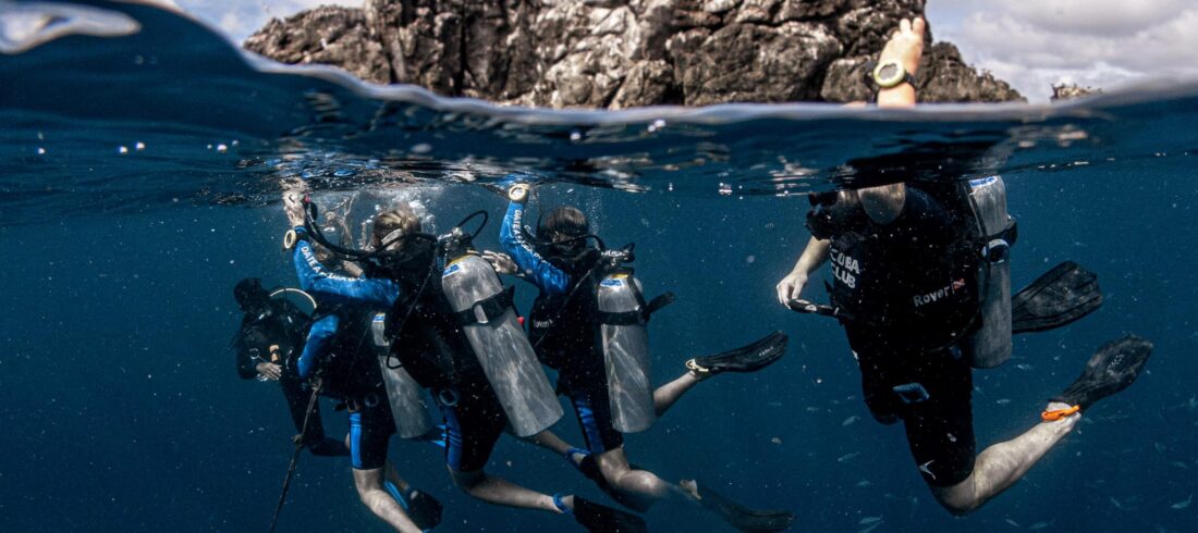 Scuba diving students practicing safety skills in Koh Tao's crystal-clear waters with their instructor.