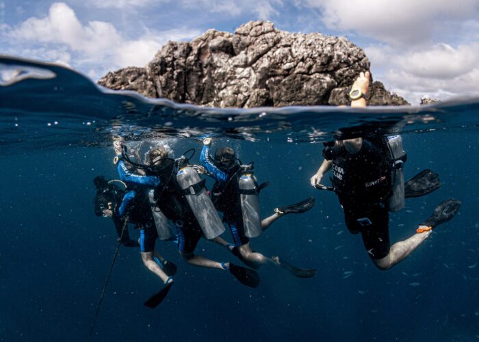 Scuba diving students practicing safety skills in Koh Tao's crystal-clear waters with their instructor.